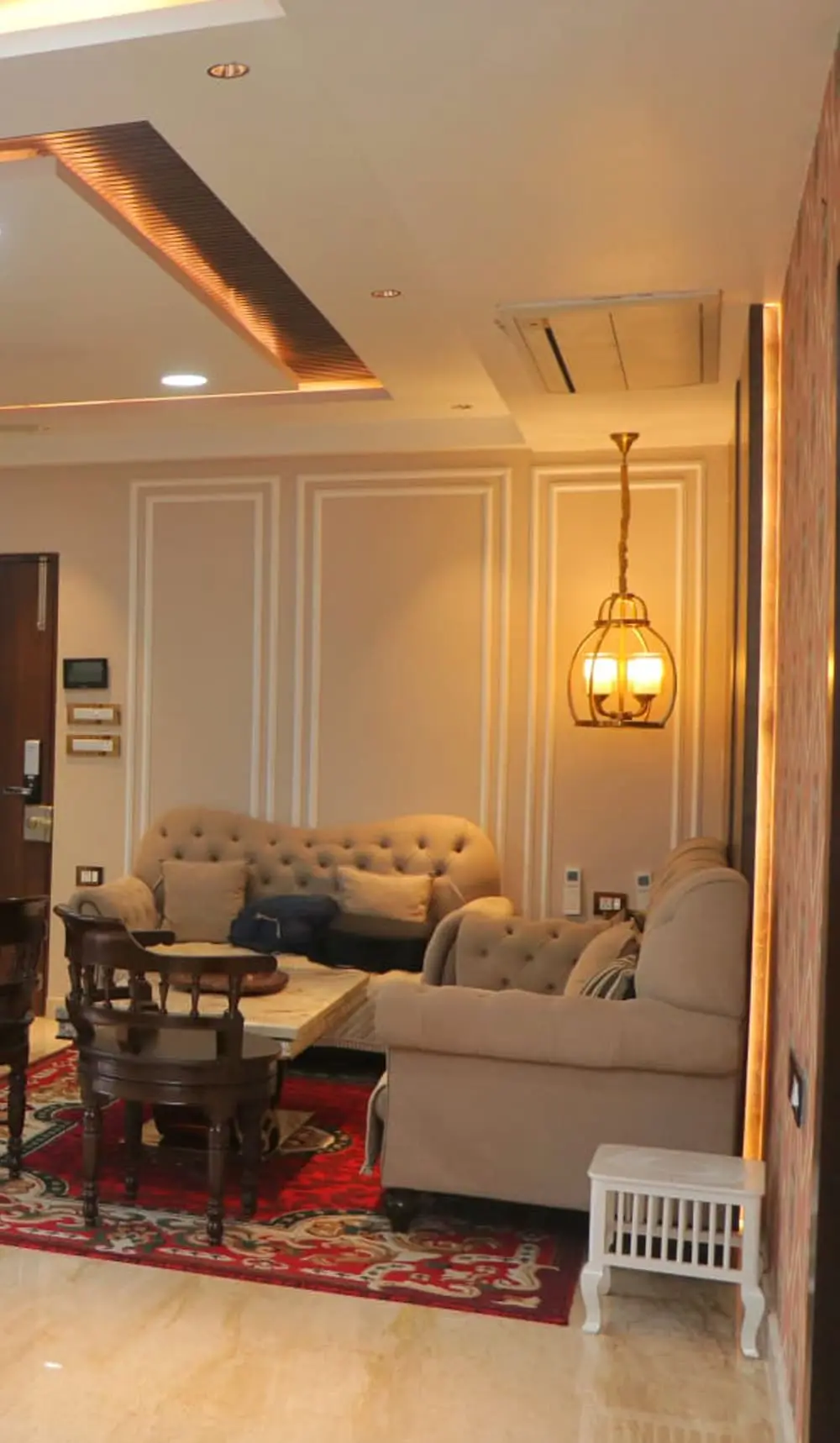 Elegant living room with tufted sofas, pendant lighting and decorative wall panels